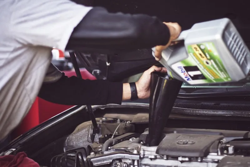 Mechanic pouring engine oil into a car