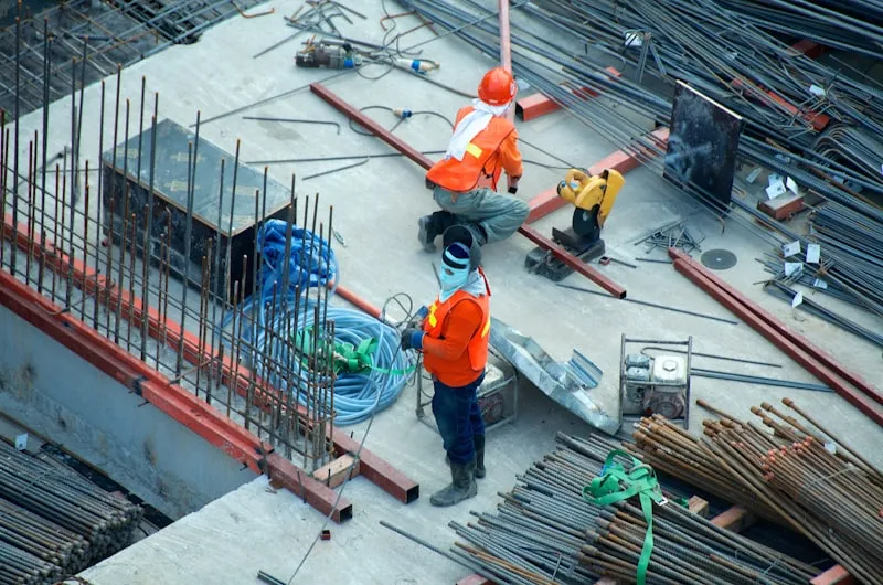 Workers in hard hats on a building site with steel reinforcing bars